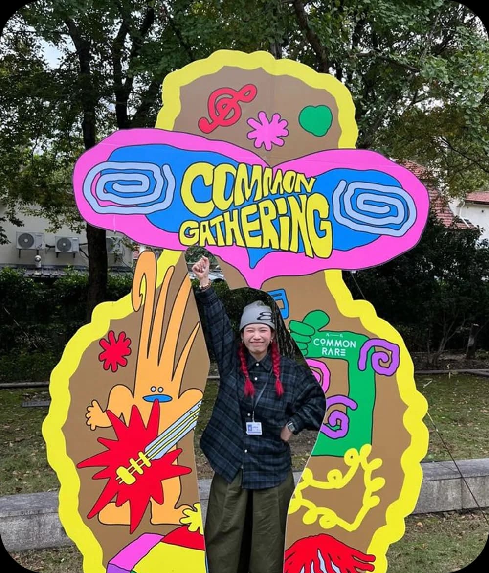 Person in front of a colourful Common Gathering art cutout